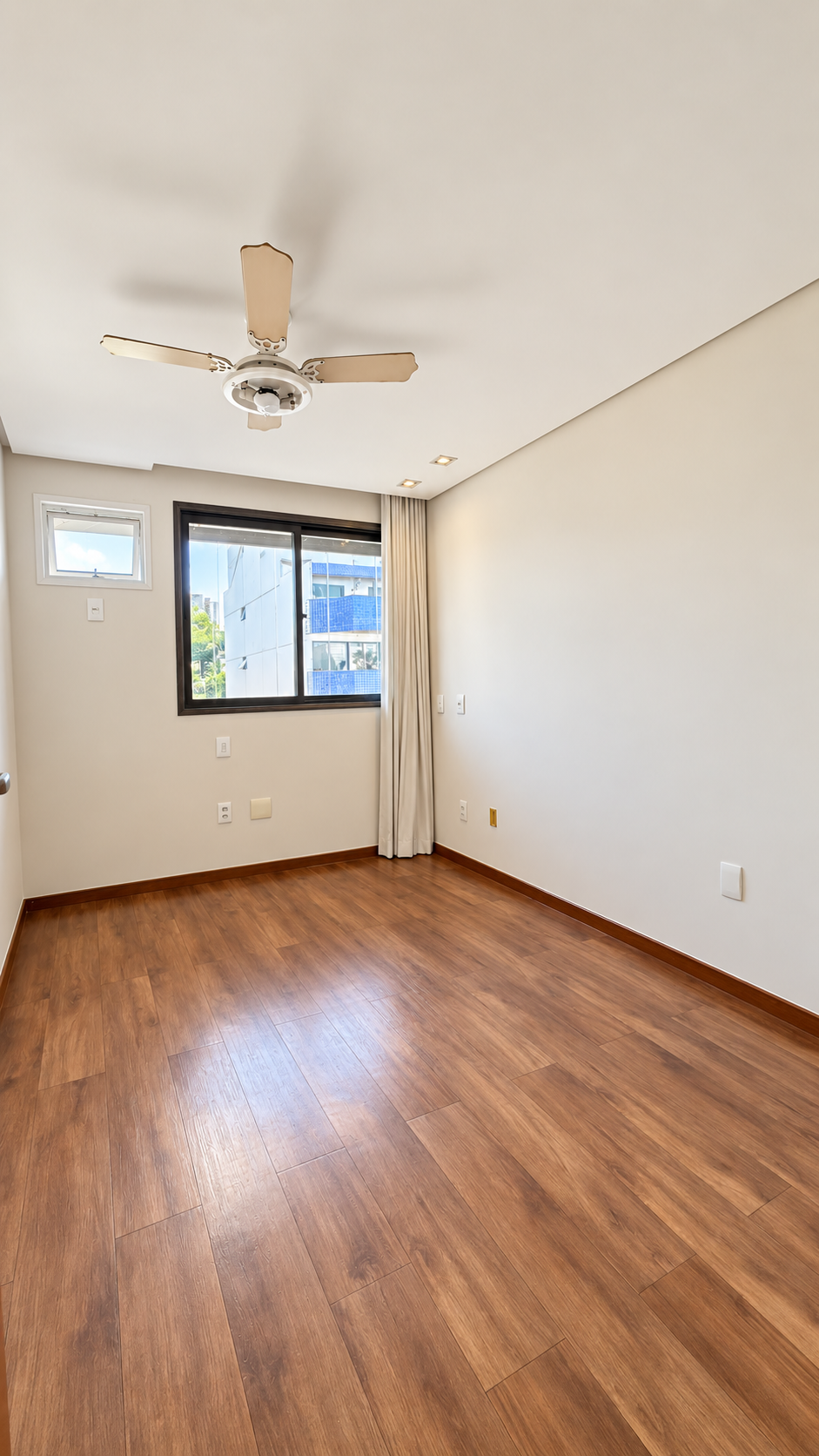 Quarto com piso amadeirado e janela