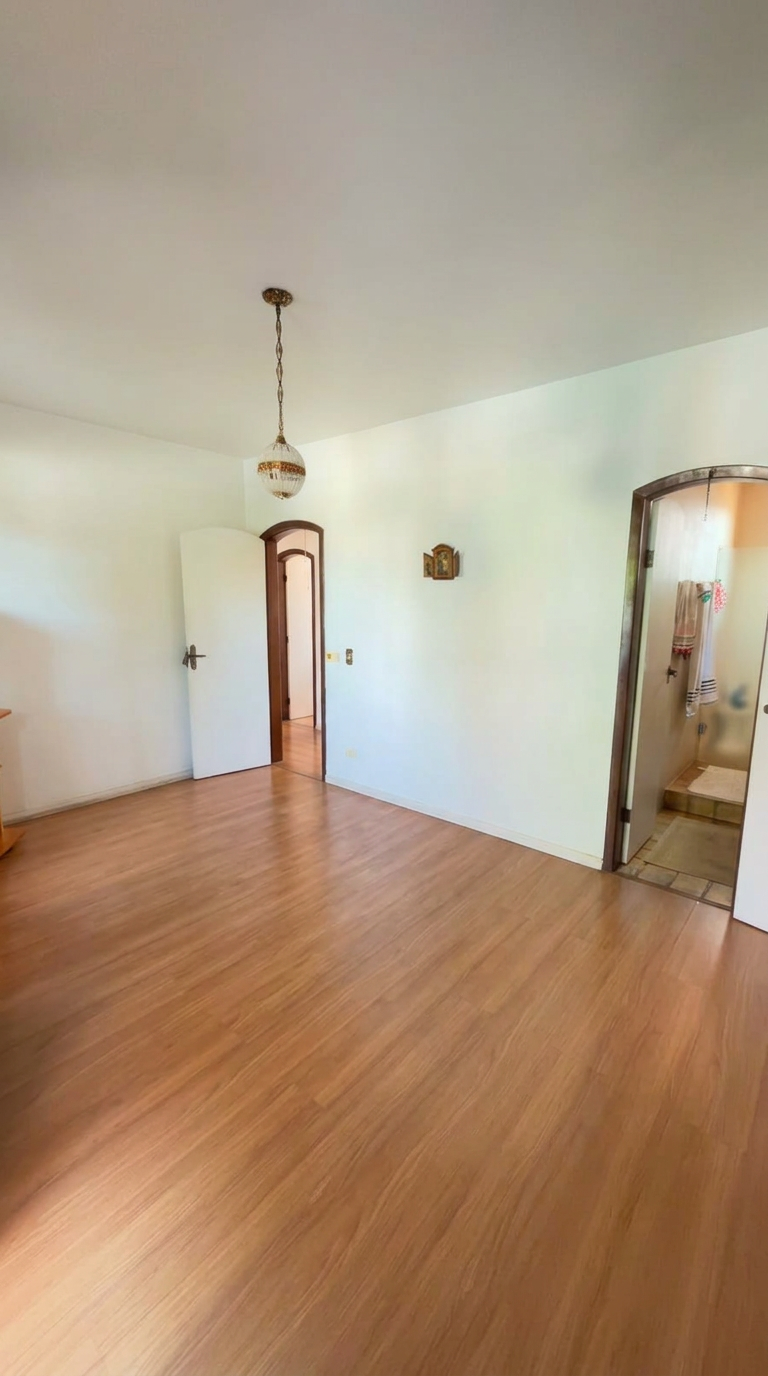 Quarto amplo com piso amadeirado e banheiro